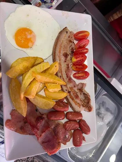 Desayuno Xavi Pinchos: huevo frito, panceta, bacon, salchichas, patatas y tomates cherry en un plato